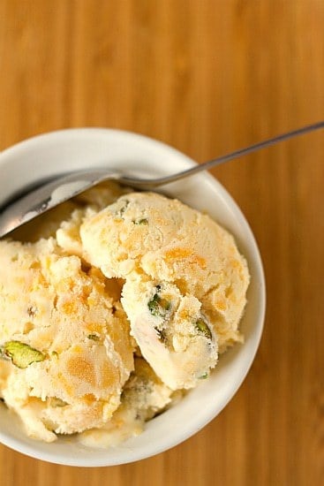 Overhead image of scoops of dried apricot pistachio ice cream in a white bowl with a spoon.