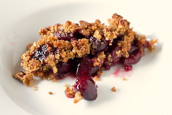 A serving of cherry crisp in a white bowl.