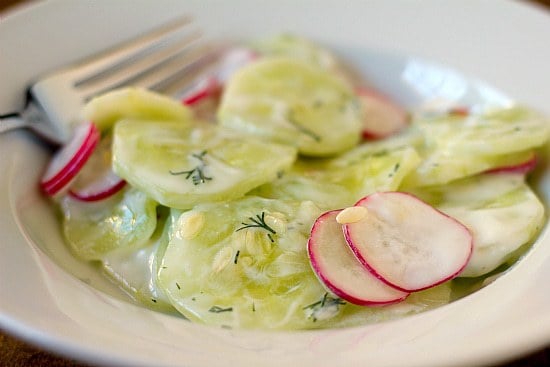 Creamy cucumber salad in a white bowl with a fork.