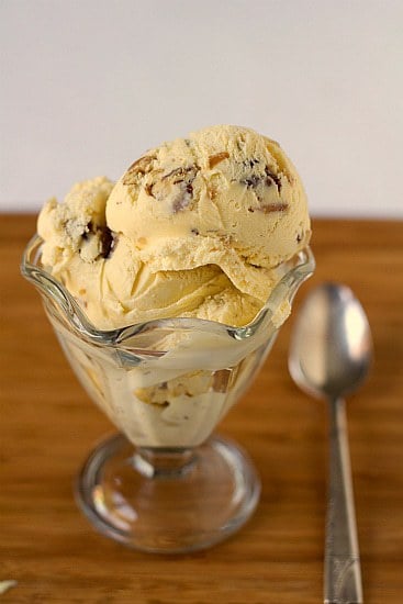 Scoops of date, rum, and pecan ice cream in a glass bowl with a spoon.