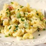 A serving of macaroni salad on a white plate.
