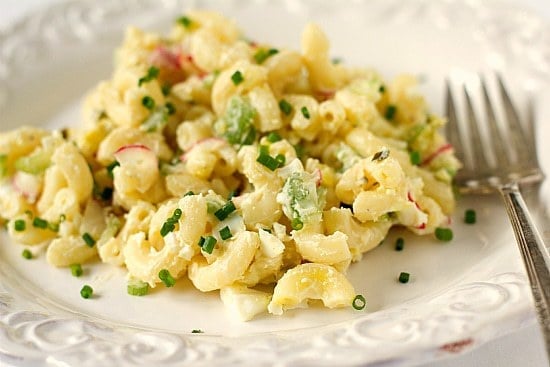 A serving of macaroni salad on a white plate with a fork.