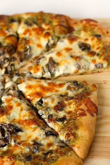 Slices of portobello pesto pizza on a wood cutting board.