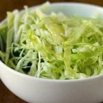 Sliced cabbage with oil and vinegar in a white bowl.