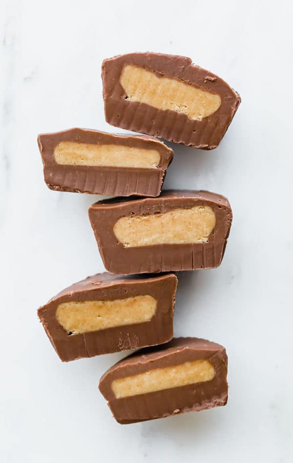 Multiple peanut butter cups cut in half, lined up, cut side up.