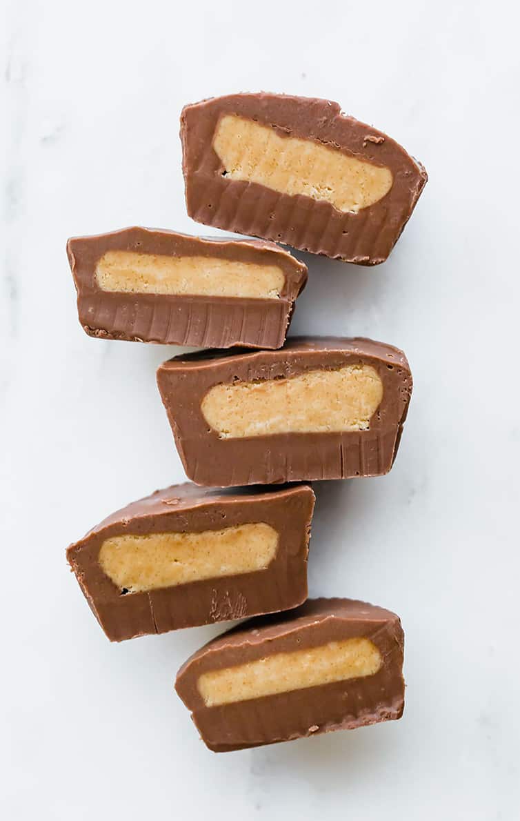 Multiple peanut butter cups cut in half, lined up, cut side up.