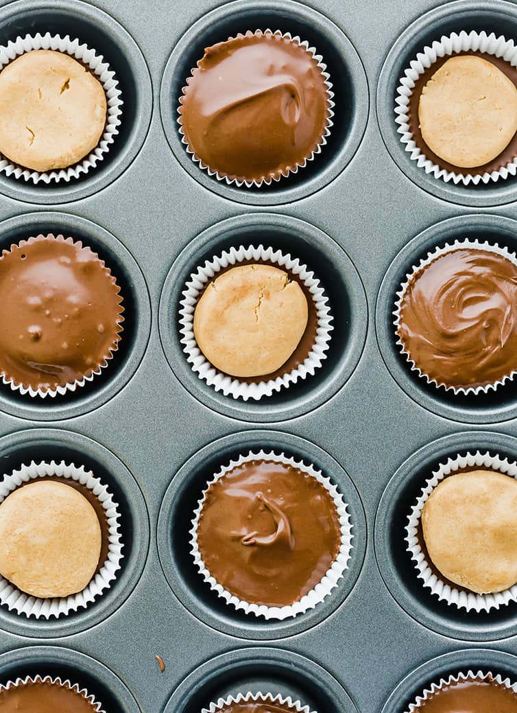 Peanut butter cups in the middle of assembly in a muffin tin.
