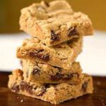 Stack of 4 peanut butter chocolate chip cookie bars on a wood surface.