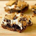 S'mores brownies cut into squares on a wood cutting board.