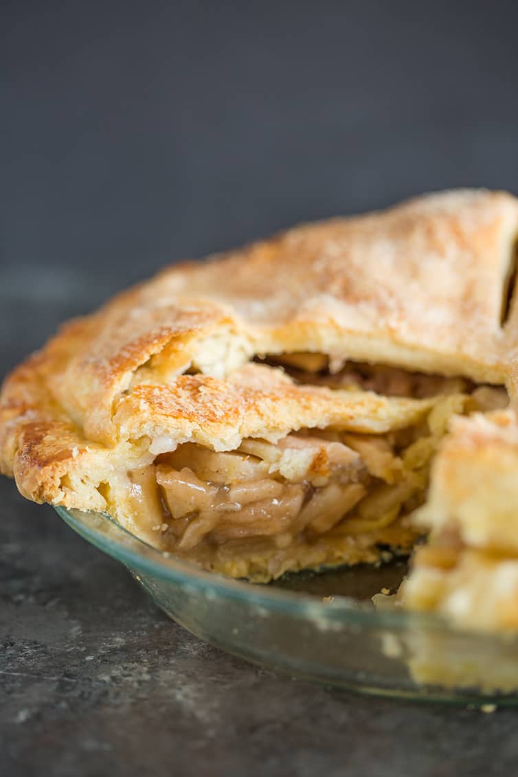 A fresh baked apple pie sliced into so you can see the filling.