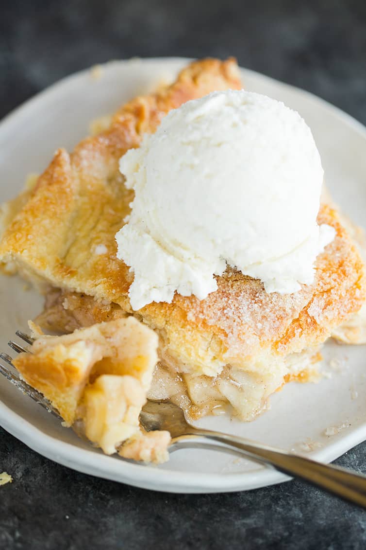 A slice of apple pie with a scoop of vanilla ice cream on top.