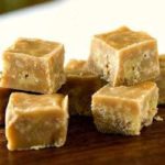 Squares of maple walnut fudge on a wood board.