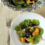 Overhead image of a serving of roasted butternut squash salad with cider vinaigrette in a white bowl with a fork.