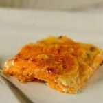 Serving of sweet potato gratin on a white plate with a fork.