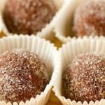 Individual chocolate bourbon balls placed in white candy wrappers.