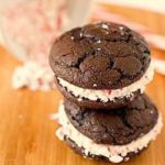 Stack of 2 chocolate peppermint whoopie pies on a wood board.