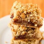 Stack of oatmeal carmelita bars on a white plate.
