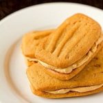 3 peanut butter sandwich cookies on a white plate.
