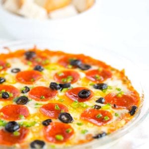 A pie plate with pizza dip and a bowl of bread cubes for dipping.