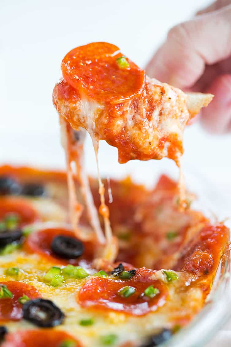 Scooping up pizza dip with a chunk of bread.