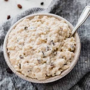 A bowl of rice pudding with raising on a dish towel.