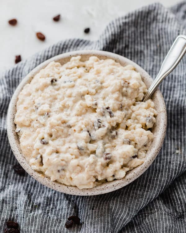 A bowl of rice pudding with raising on a dish towel.