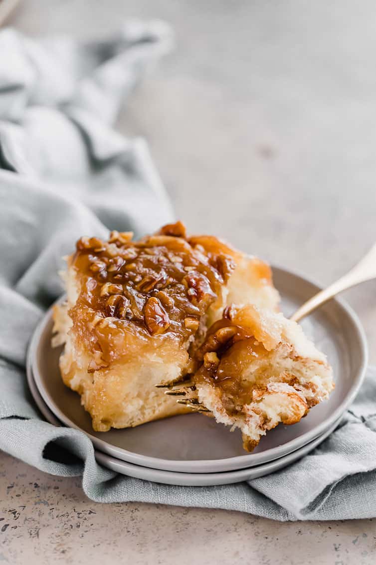 A sticky bun on a plate, with a fork taking out a bite.
