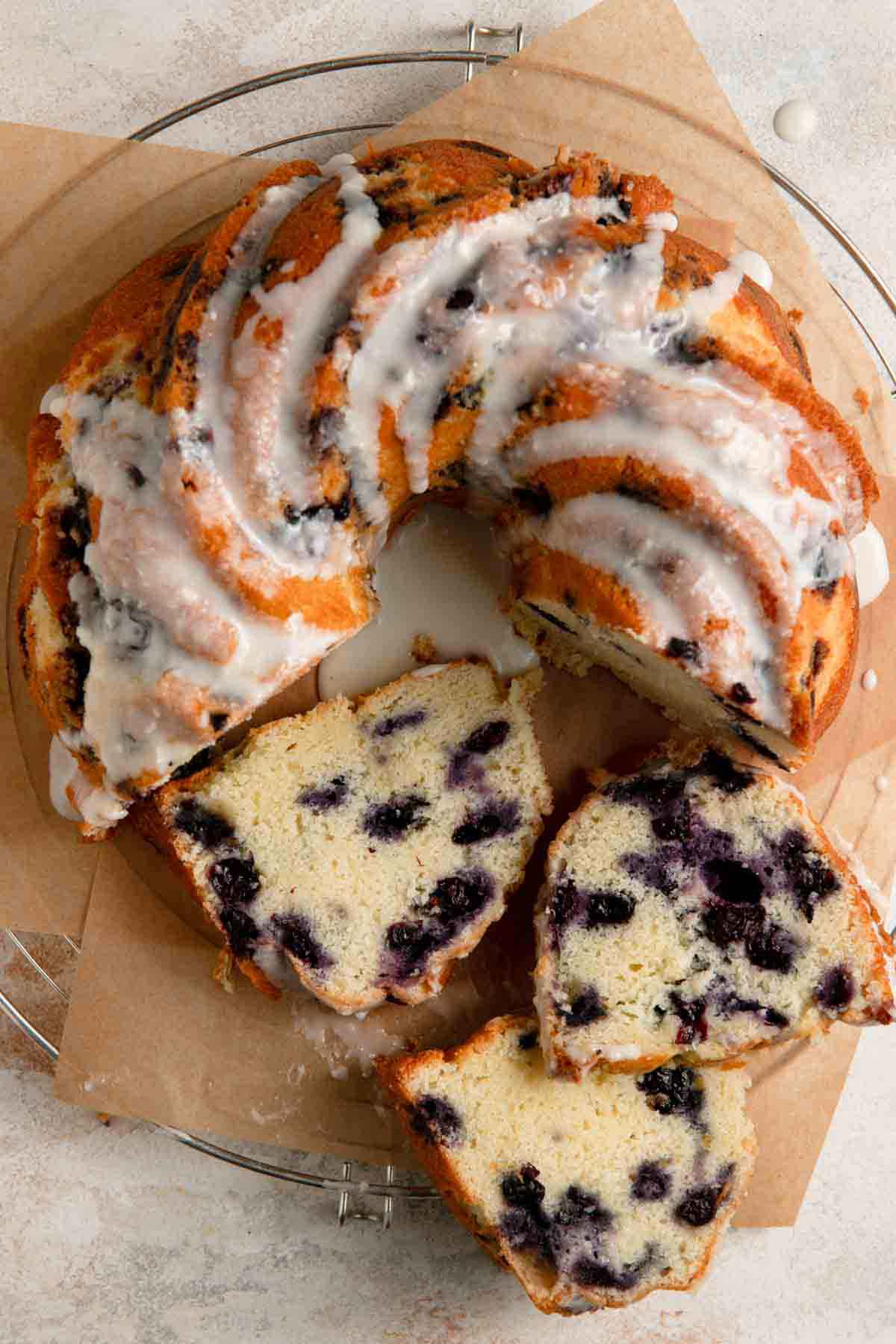 Overhead photo of a lemon blueberry bundt cake with three slices laying on their side in front of the whole cake.