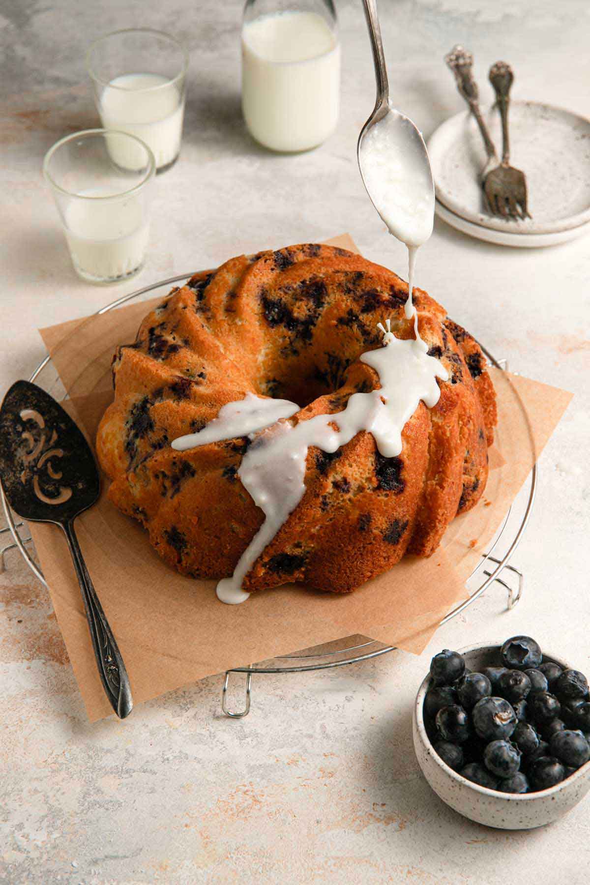 Icing being drizzled on a blueberry cake.