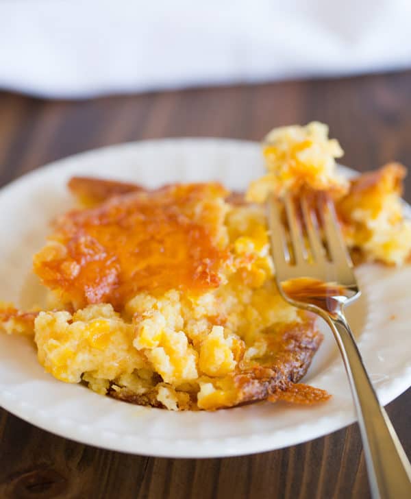 A serving of cheesy creamed corn casserole on a round plate.