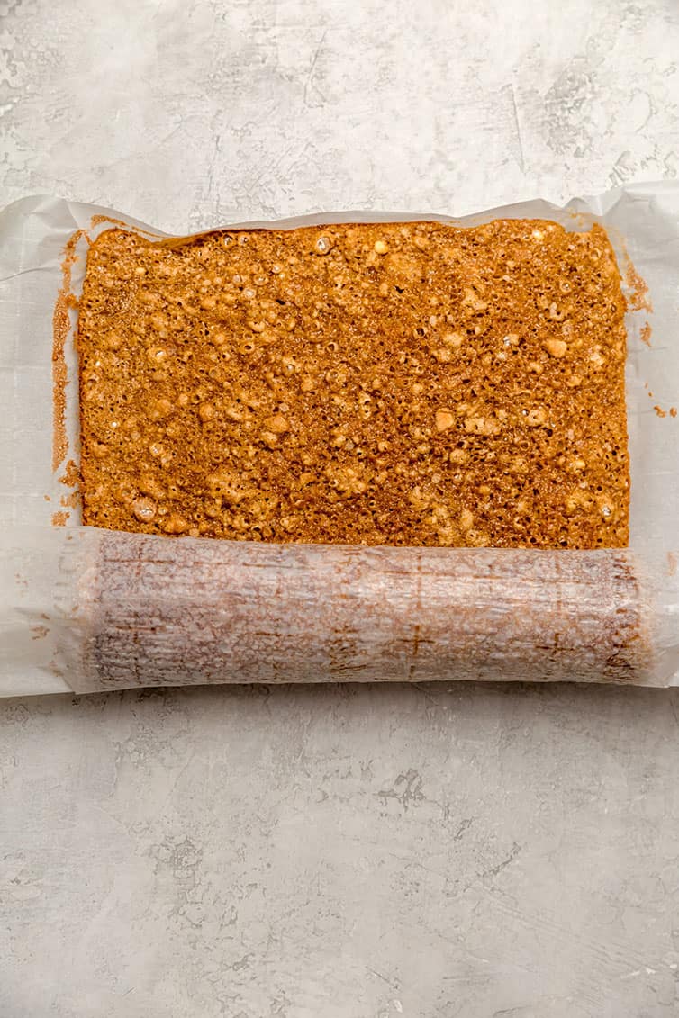 Pumpkin roll cake being rolled up in parchment paper.