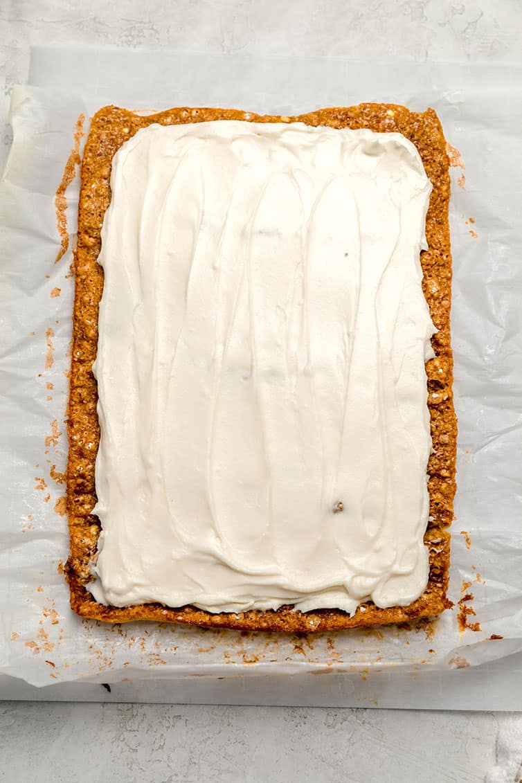 A pumpkin roll slathered with cream cheese frosting before being rolled back up.