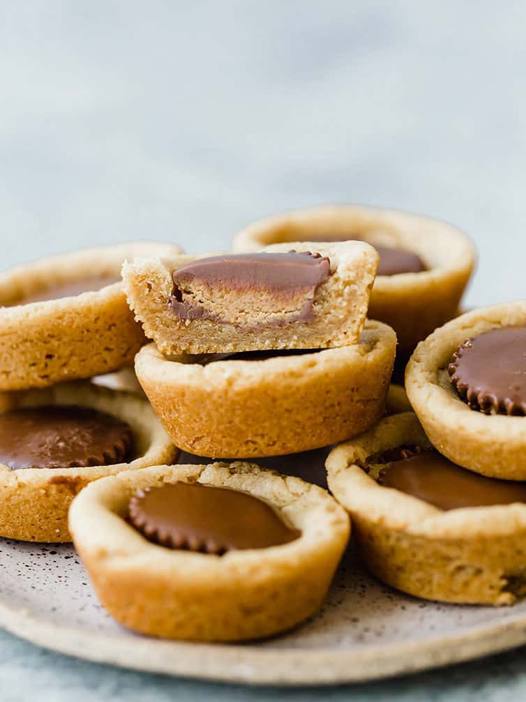 A pile of peanut butter cup cookies with half of one on the very top.