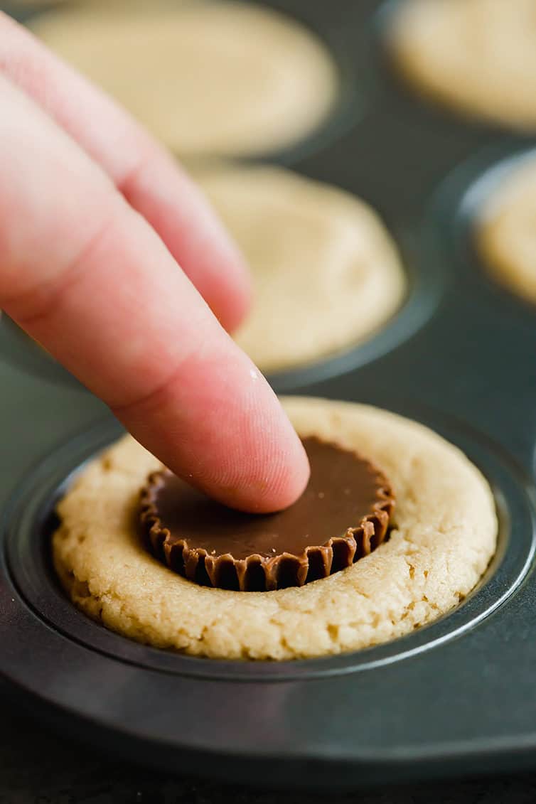 Pressing a peanut butter cup into the peanut butter cookies.