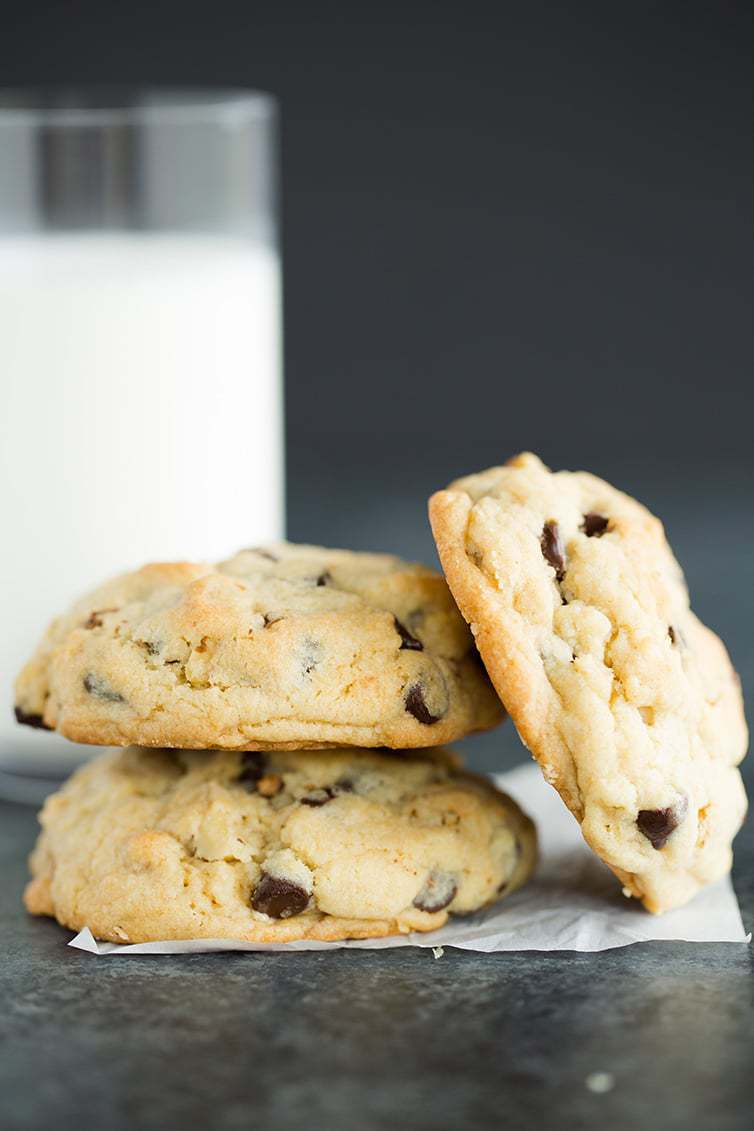 A stack of Levain chocolate chip cookies with a glass of milk.