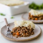 Two plates with shepherd's pie and the casserole dish in the background.