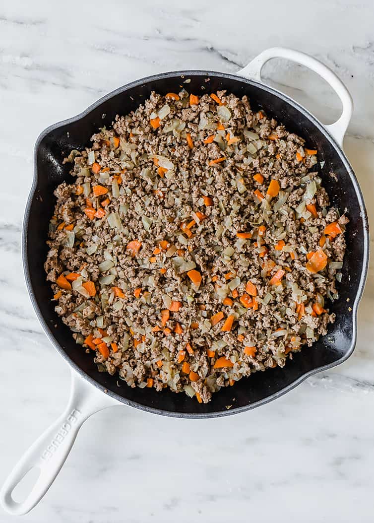 A skillet with the cooked meat mixture for shepherd's pie.