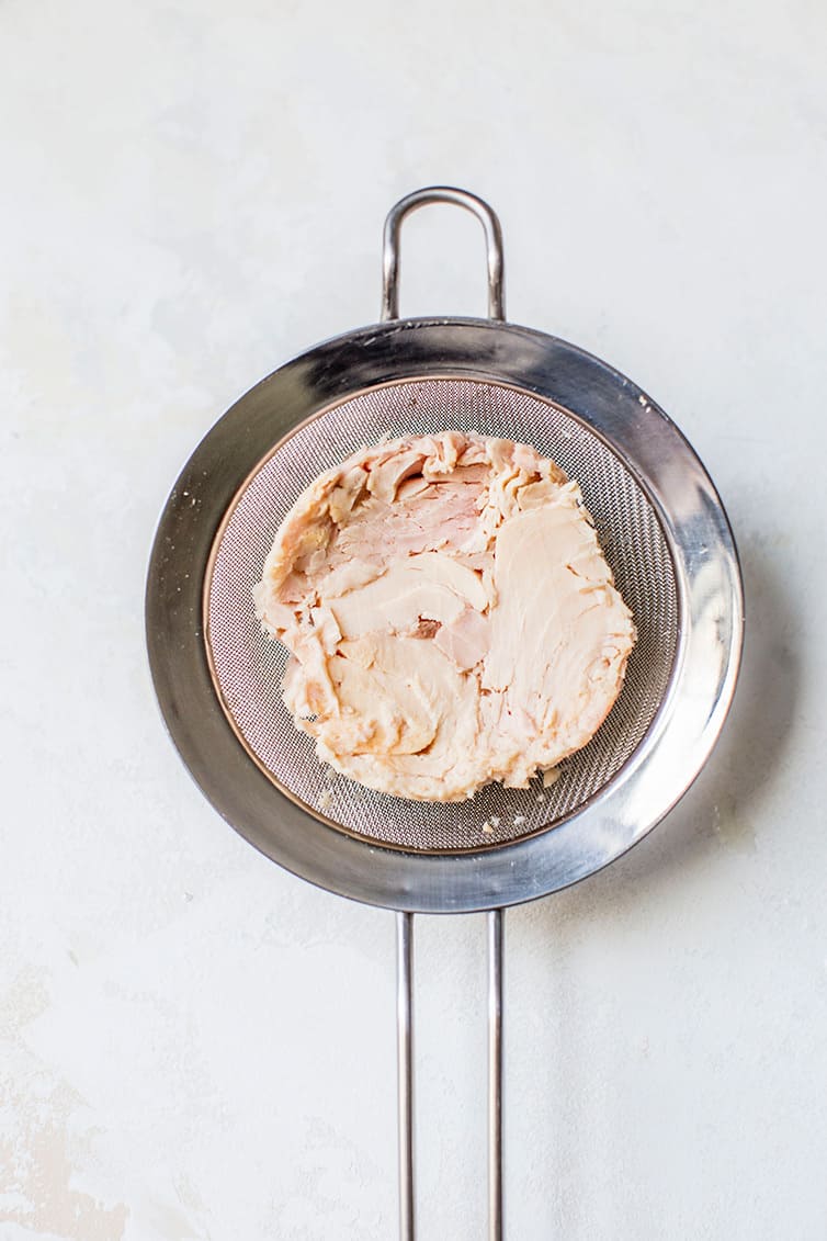 Tuna draining in a fine mesh sieve.