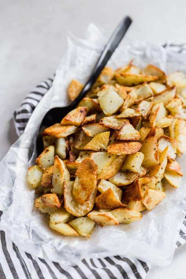 Bowl of roasted potatoes with a serving spoon.