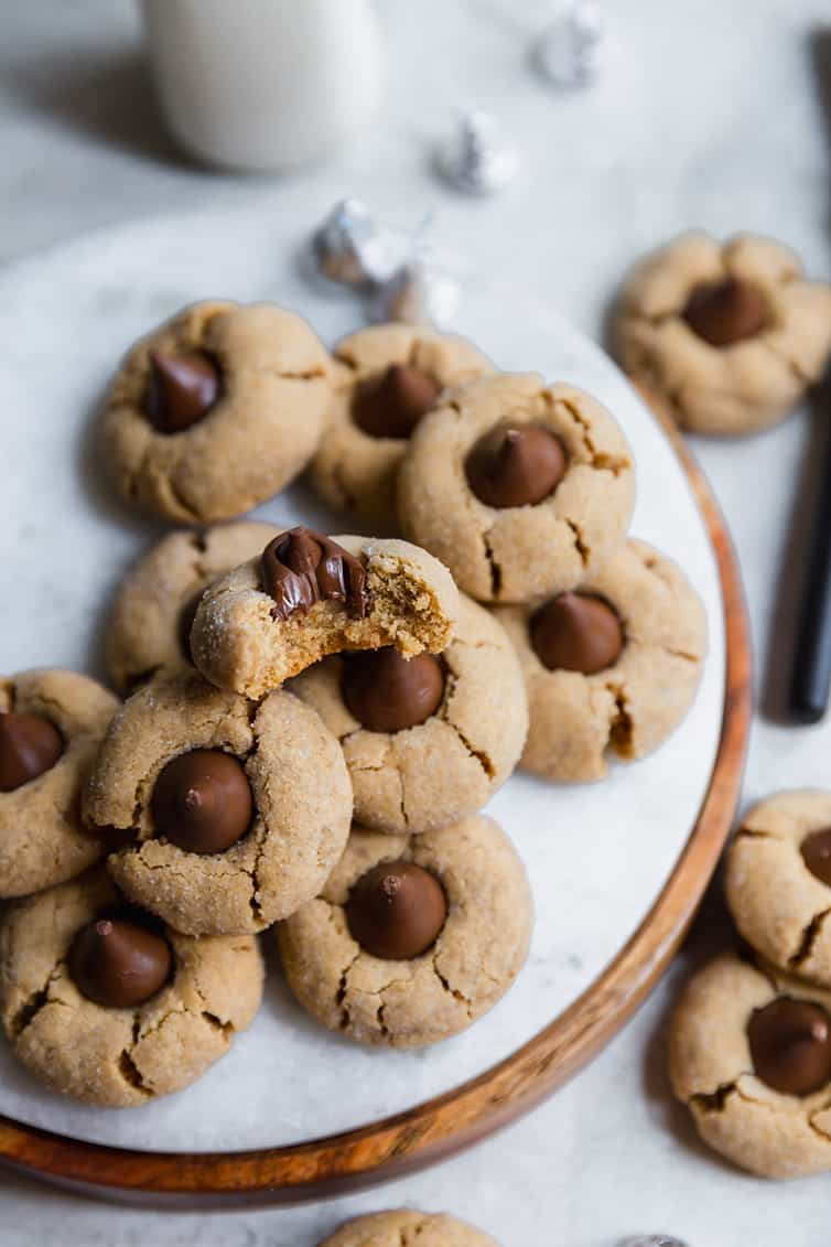 Peanut Butter Blossoms on a marble serving tray, with one bitten in half.