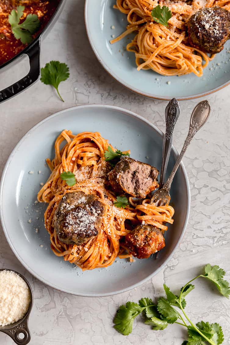 An overheat shot of two plates of spaghetti and meatballs.