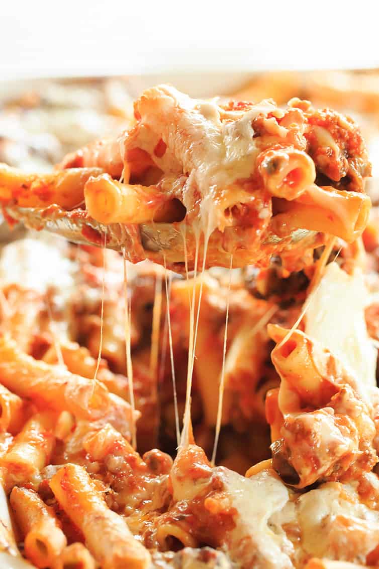 A spoonful of baked ziti being scooped out the pan.