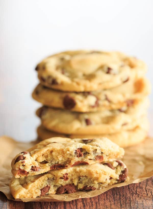 One chocolate chip cookie split in half in front of a stack of cookies.