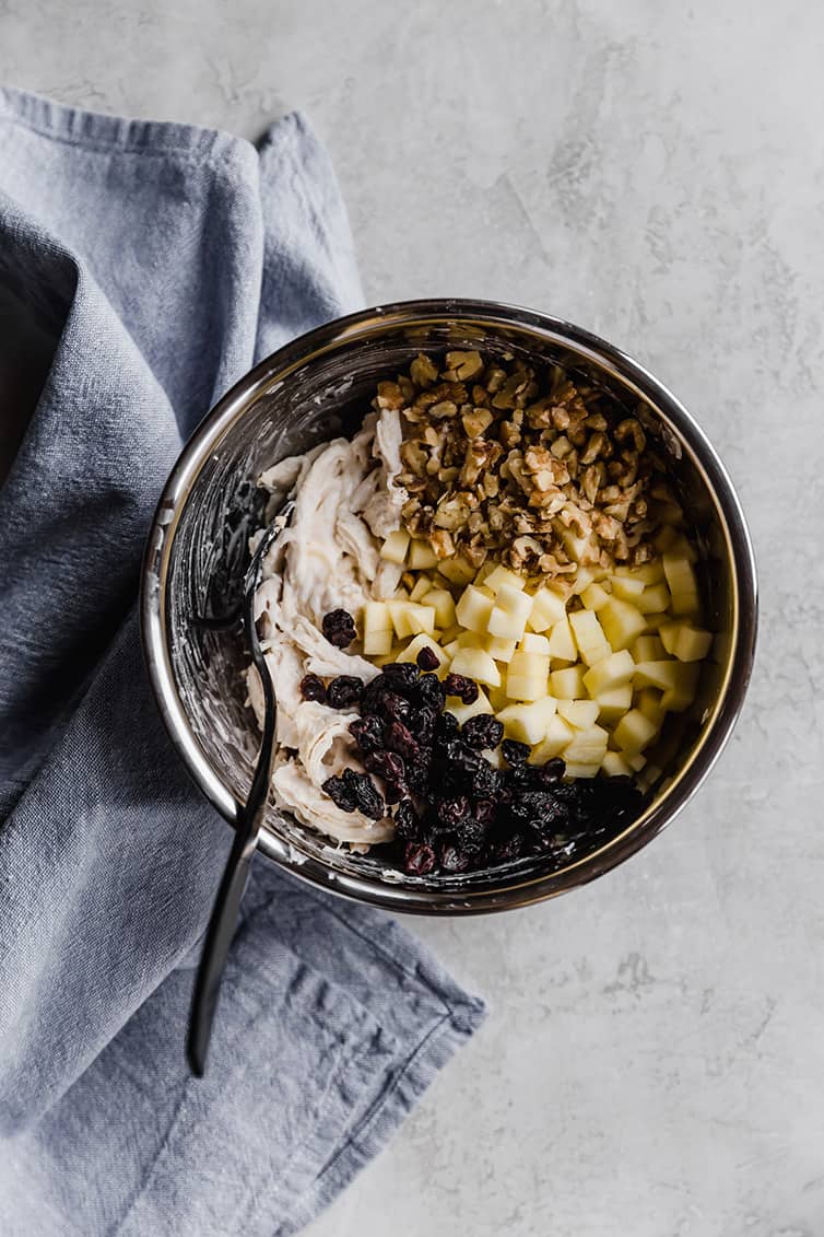A mixing bowl with all of the ingredients for chicken salad.