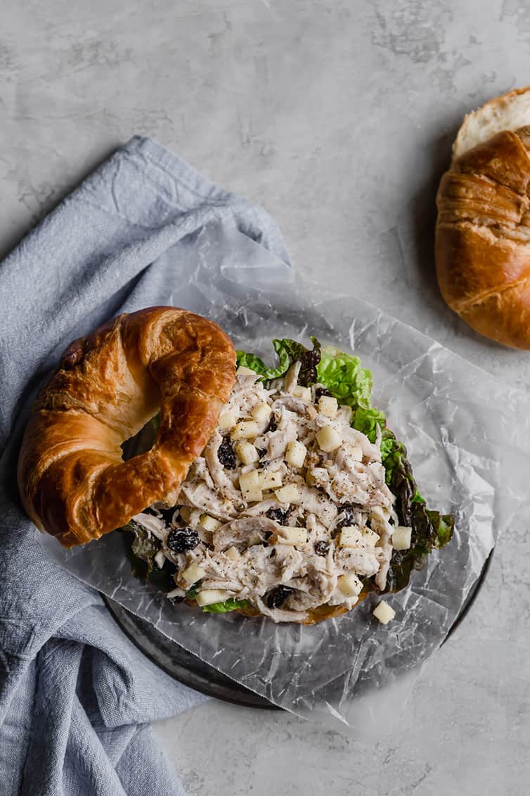 A chicken salad sandwich on croissant with the top off.