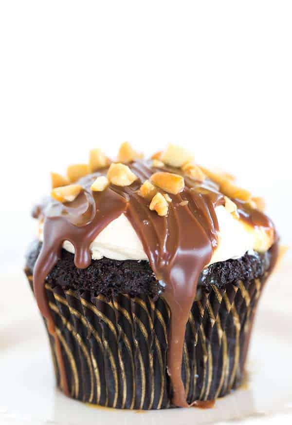 These Snickers cupcakes taste JUST like the candy bar... A chocolate cupcake filled with peanut nougat, topped with a caramel buttercream frosting, covered in a chocolate ganache, chopped peanuts and a drizzle of caramel sauce.