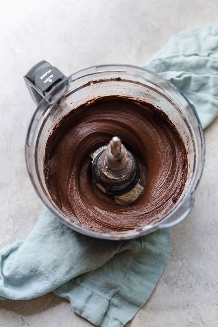 Chocolate frosting in the bowl of a food processor.