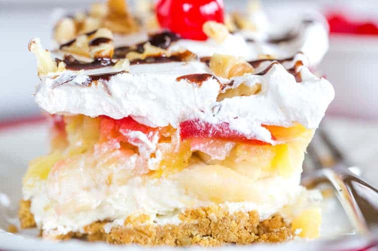 No Bake Banana Split Dessert is a classic! It layers a graham cracker crust, cream cheese-based filling, bananas, pineapple, strawberries, whipped cream, nuts, chocolate & a cherry on top!