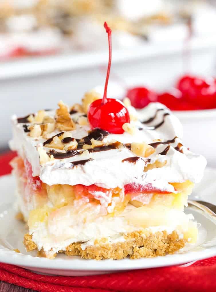No Bake Banana Split Dessert is a classic! It layers a graham cracker crust, cream cheese-based filling, bananas, pineapple, strawberries, whipped cream, nuts, chocolate & a cherry on top!