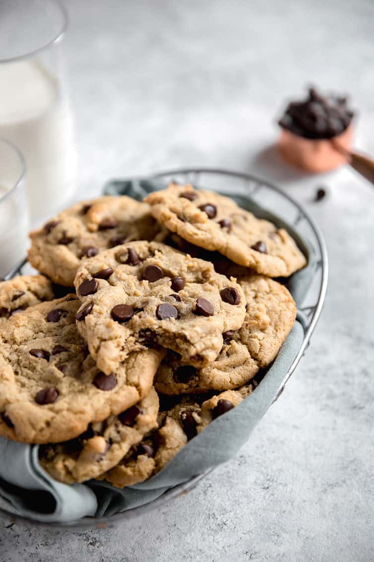 A basket of chocolate chip cookies, with a bite taken out of one.